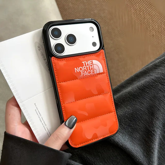igh-gloss orange quilted puffer jacket phone case with camera lens protection guard for iPhone 17 Pro Max held in hand.
